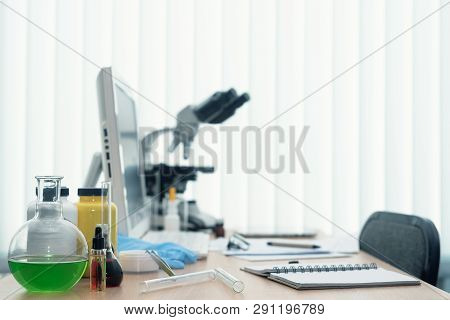 Laboratory Table With Microscope, Flasks And A Desktop Computer Above On A Window Light Background. 