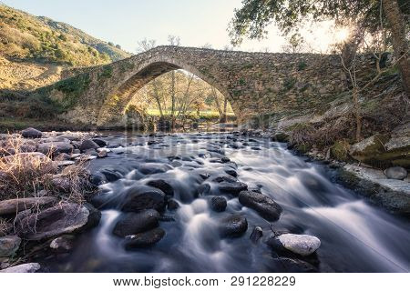 Ancient Stone Bridge Over Flowing River In Corsica