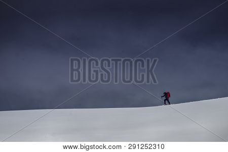 A Lone Alpinist Walking On Skiers Across The Horizon