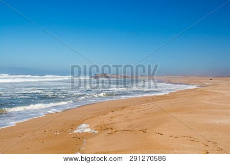 Atlantic Ocean With Intense Waves During A Windy Autumn Day. Empty Beach With Golden Sand. Blue Sky 
