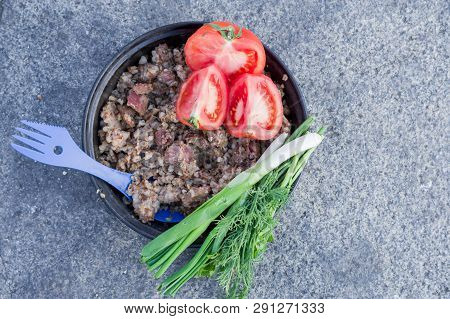 Dish cooked in nature. Porridge and salad. Top view on the dish.