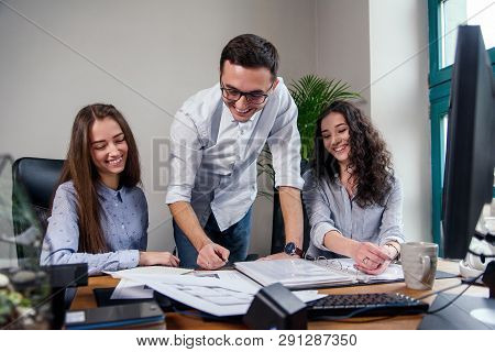 Handsome Firm Manager In Glasses Explains Work Tasks For His Employees. Creative People Or Advertisi