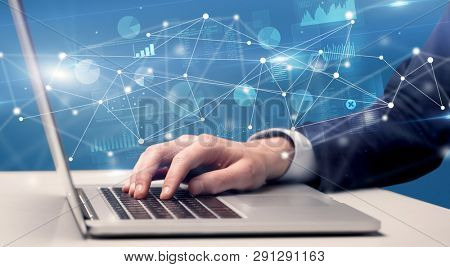 Businessman typing on laptop with linked reports charts grapghs around