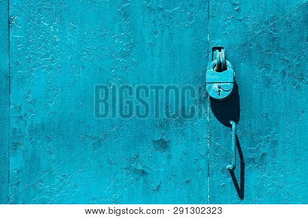 Closed Imperfect Blue Garage Gate With Padlock Close-up. Texture Of Locked Iron Door With Cyan Peeli