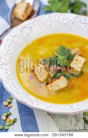 Soup Of Split Peas And Smoked Ribs With Croutons In A Plate On An Old Wooden Table, Selective Focus.
