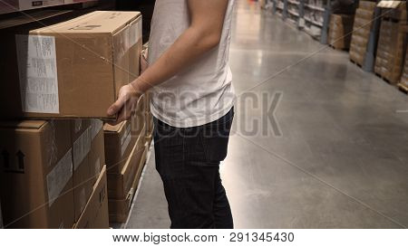 Warehouse Large Storage Or Logistic Or Cargo For Distribution. And Man's Hand Is Picking Up A Box.