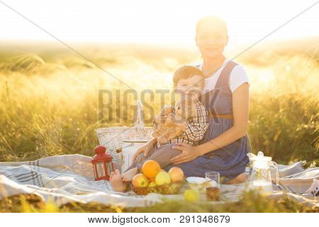 Pregnant Mom And Her Beautiful Little Son At A Picnic. Happy Family And Healthy Eating Concept