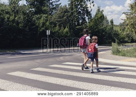 Kids With Backpacks Walking Through Pedestrian Crossing To The School