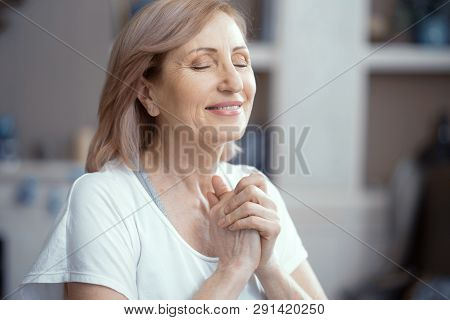 Beautiful Woman Over 50 Years Old Enjoys Yoga. She Is Meditating By Cupping Her Palms In Front Of He