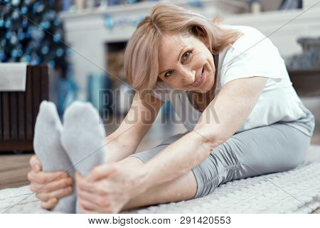 A Woman Over 50 Years Old Enjoys Yoga. She Took The Position Of Asana On The Floor. Woman Loves To D