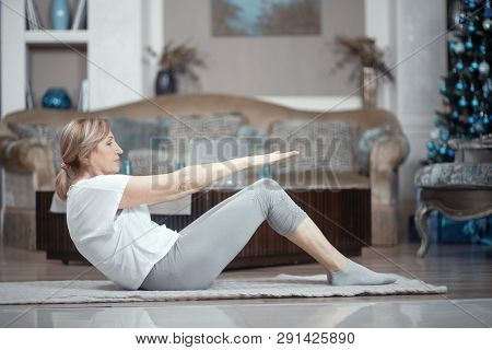 A Woman Over 50 Years Old Doing Yoga At Home. Lying On The Floor She Performs Exercises Asana. A Wom
