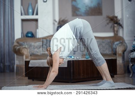 Adult Woman Does Yoga. At Home In The Living Room She Does Yoga Exercises On The Yoga Mat.