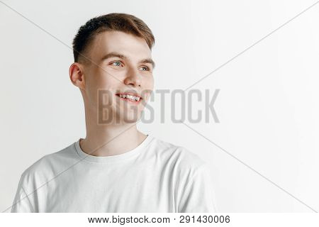 Looking For The Best Moment. Young Dreaming Smiling Man Is Waiting For Chanses Isolated On Gray Back
