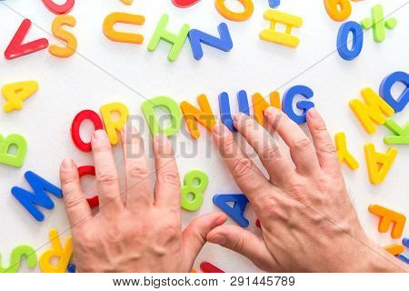 Lots Of Colorful Letters On A Table, Hands Forming German Word Ordnung, Which Means Keep Order