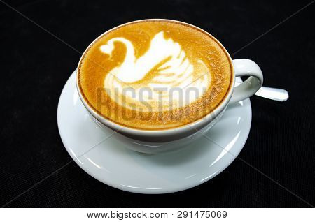 Cappuccino With Swan Drawn On The Foam, In A White Cup With Spoon And Saucer, Black Background