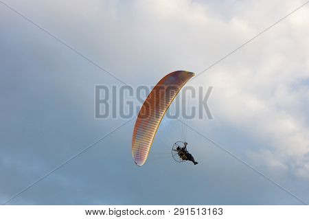 Silhouette Paramotor Flying On Cloudy Sky Background