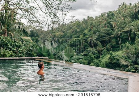 Human relaxing in Bali infinity pool with jungle view 