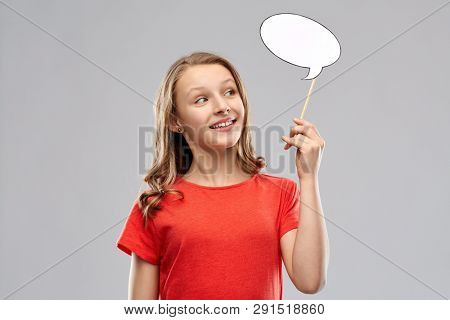 communication and people concept - smiling teenage girl with long hair in red t-shirt holding blank speech bubble over grey background