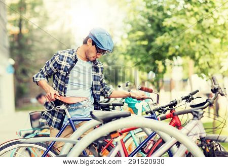 people, style, leisure and lifestyle - hipster man parking fixed gear bike on city street