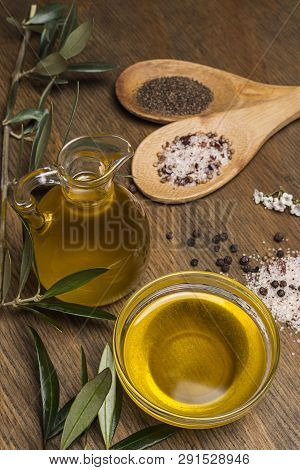 Olive Oil, Two Spoon With Salt And Pepper On A Wooden Table