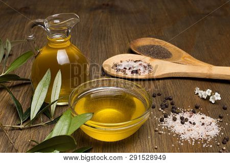 Olive Oil, Two Wooden Spoon With Salt And Pepper On A Wooden Table