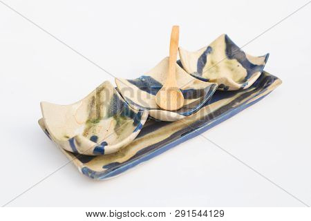 Three Wells Of Ceramic Stoneware And Wooden Spoons With White Background