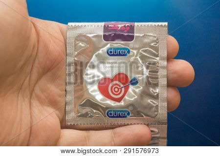 Tyumen, Russia - February 01, 2019: Durex Condom In Hand On Blue Background Close-up. Used To Preven