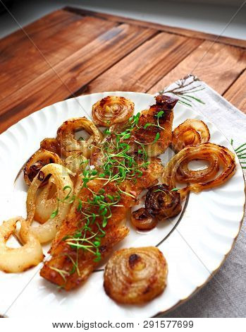 Grilled Fish On White Plate With Onions And Micro Greens