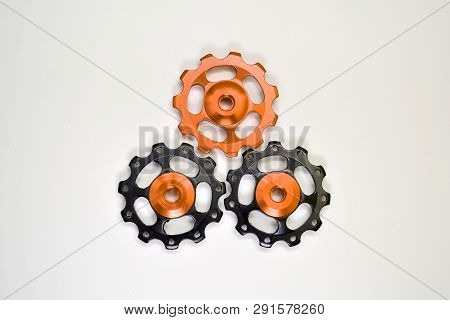 Color Rollers, Black, Golden Gears For Bicycle Rear Derailleur On White Background In Shape Of Trian