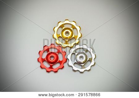 Color Rollers, Black, Golden, Silver Gears For Bicycle Rear Derailleur On White Background In Shape 