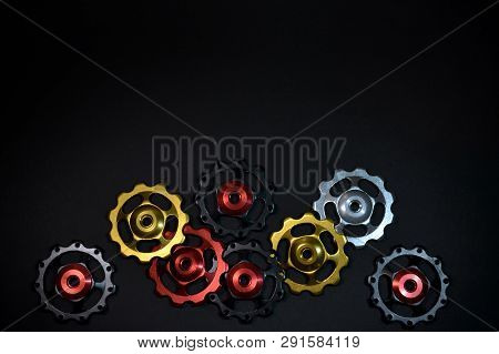Colored Rollers, Black, Red, Gold Gears For Bike Rear Derailleur Placed Chaotically In Bottom Side O