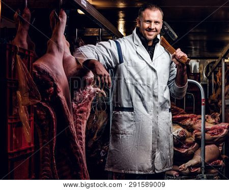 The Butcher In A White Work Shirt Holding Ax And Smiling While Standing In A Refrigerated Warehouse 