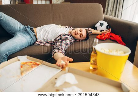 Male football fan sleeping on couch at home