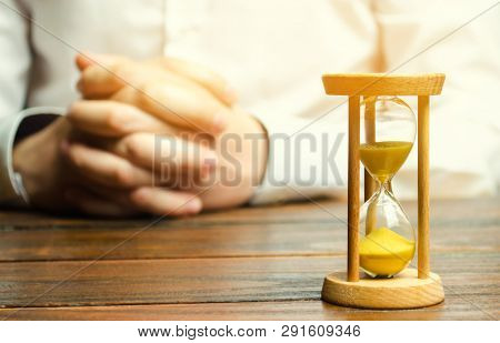 An Hourglass And Businessman Holds His Hands In The Lock. Job Interview Concept. Business Planning. 