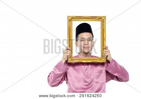 Portrait Of Young And Handsome Asian Man With Traditional Clothing Holding Blank Frame Over White Ba