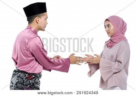 Portrait Of Young Man With Traditional Clothing Shaking Hand His Wife During Hari Raya Over White Ba