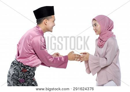 Portrait Of Young Man With Traditional Clothing Shaking Hand His Wife During Hari Raya Over White Ba