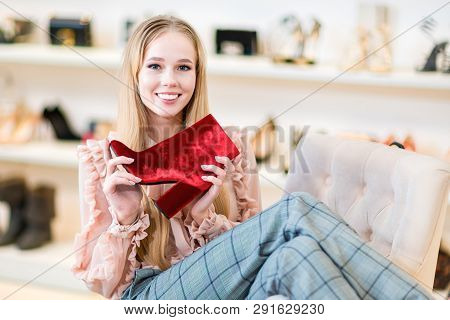 Shopping. Smiling Girl Chose Red Shoes. Joy And Good Mood.