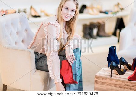 Shopping. Smiling Girl Chose Red Shoes. Joy And Good Mood.