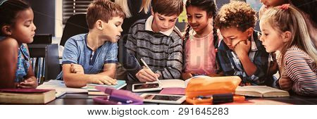 Teacher helping schoolgirl with her homework in classroom at school