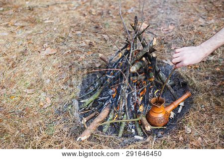 At The Stake In The Spring Forest, A Clay Turkish Coffee Pot Is Heated Against The Grass. In The Fra