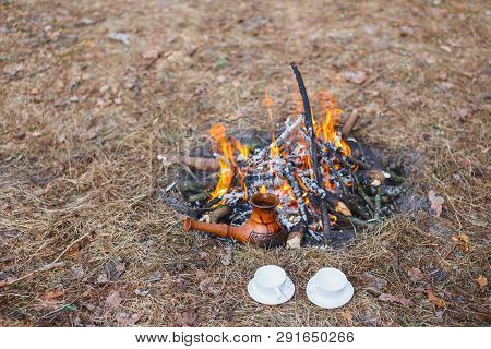 At The Stake In The Spring Forest, A Clay Turkish Coffee Pot Is Heated Against The Grass.