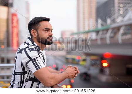 Profile View Of Young Bearded Indian Man Against View Of The City Outdoors