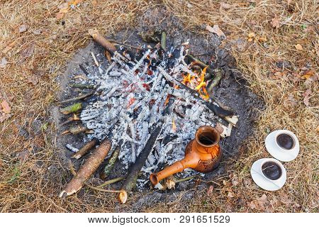 At The Stake In The Spring Forest, A Clay Turkish Coffee Pot Is Heated Against The Grass.