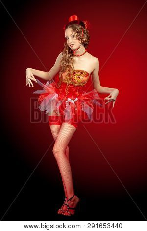 Sexy burlesque dancer stripper posing with sweet lollipop, in red corset and red hat with curly hair