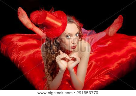 Sexy Burlesque Dancer Stripper Posing With Sweet Lollipop, In Red Corset And Red Hat With Curly Hair
