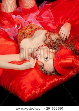 Sexy Burlesque Dancer Stripper Posing With Sweet Lollipop, In Red Corset And Red Hat With Curly Hair