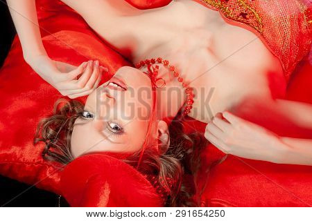 Sexy Burlesque Dancer Stripper Posing With Sweet Lollipop, In Red Corset And Red Hat With Curly Hair