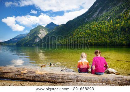 Two Cute Sisters Enjoying The View Of Deep Green Waters Of Konigssee, Known As Germany's Deepest And