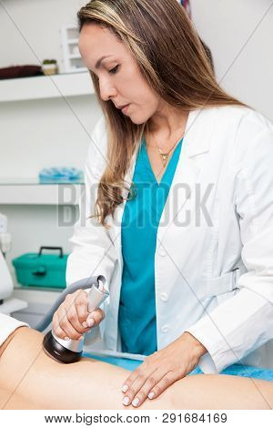 Doctor Performing An  Ultracavitation Treatment On A Young Female Patient Leg